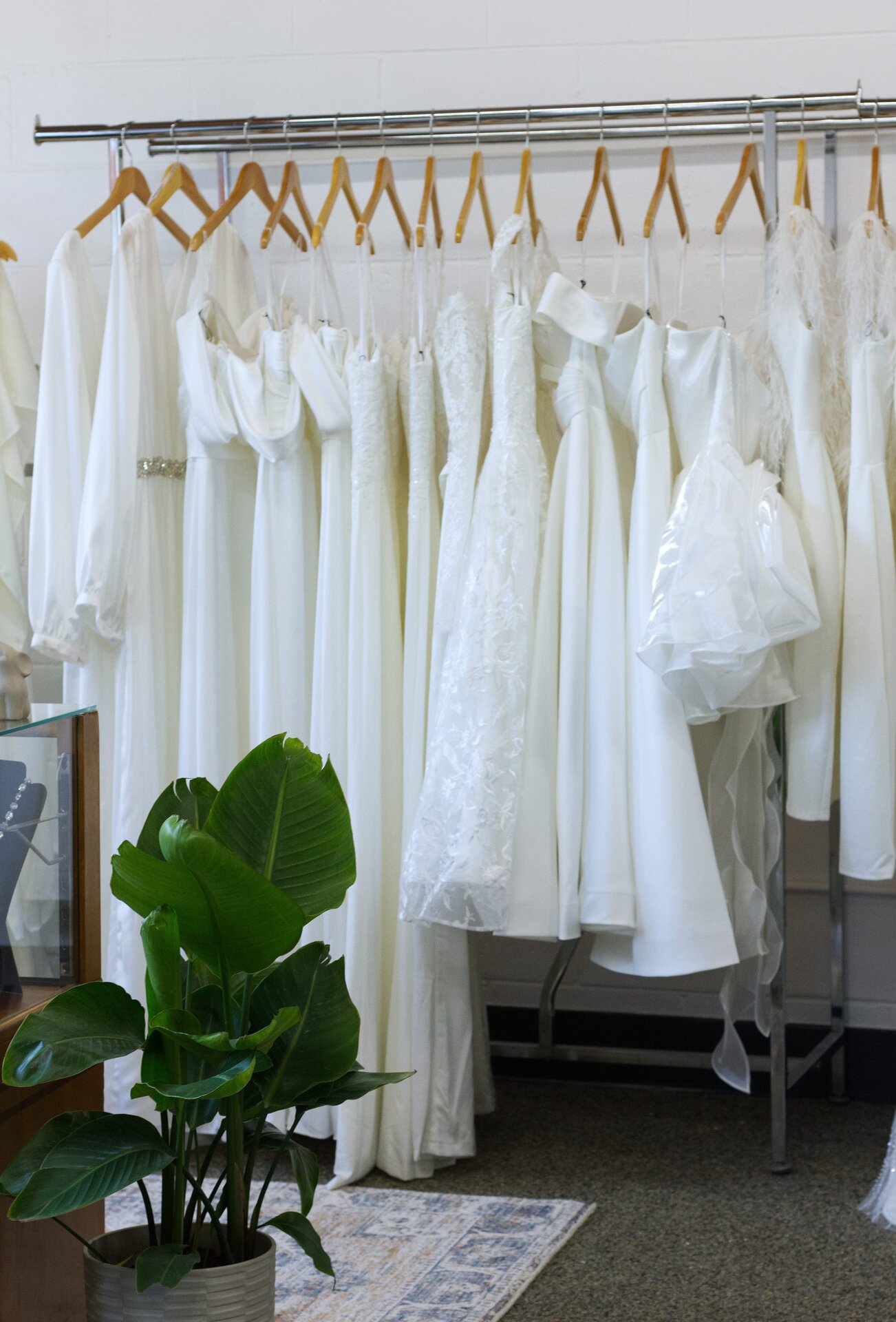 A rack of white bridal jumpsuits and short white wedding dresses.